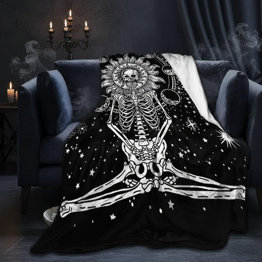 A black throw blanket with a white skeleton design draped over a dark gray armchair in a living room setting.