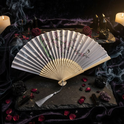 Handheld fan with floral design on a light background with pink flowers