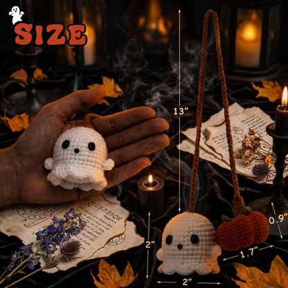 A crocheted Halloween ghost keychain shown with size annotations and a hand holding it for scale. The ghost is white with black eyes and a small orange pumpkin charm hangs from an orange-brown rope.