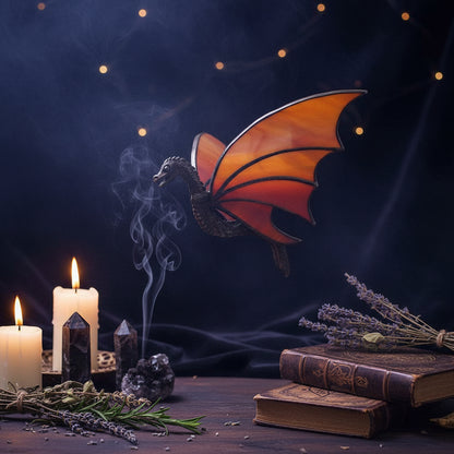 Dragon-shaped stained glass window light with orange wings and a dark metallic body, shown on a white background with two circular inset photos demonstrating use in a window and in a hand.