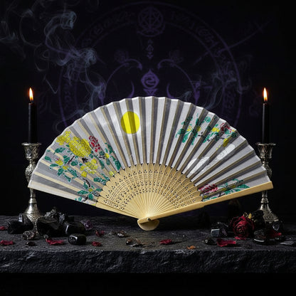 Decorative folding fan with floral patterns on a white tray with pink flowers.