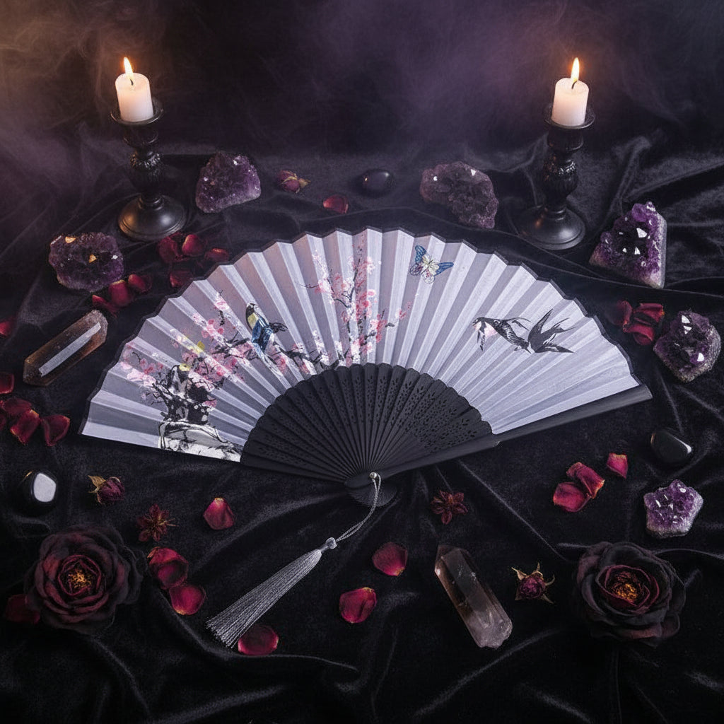 Handheld fan with floral and bird design on a white background with pink flowers.