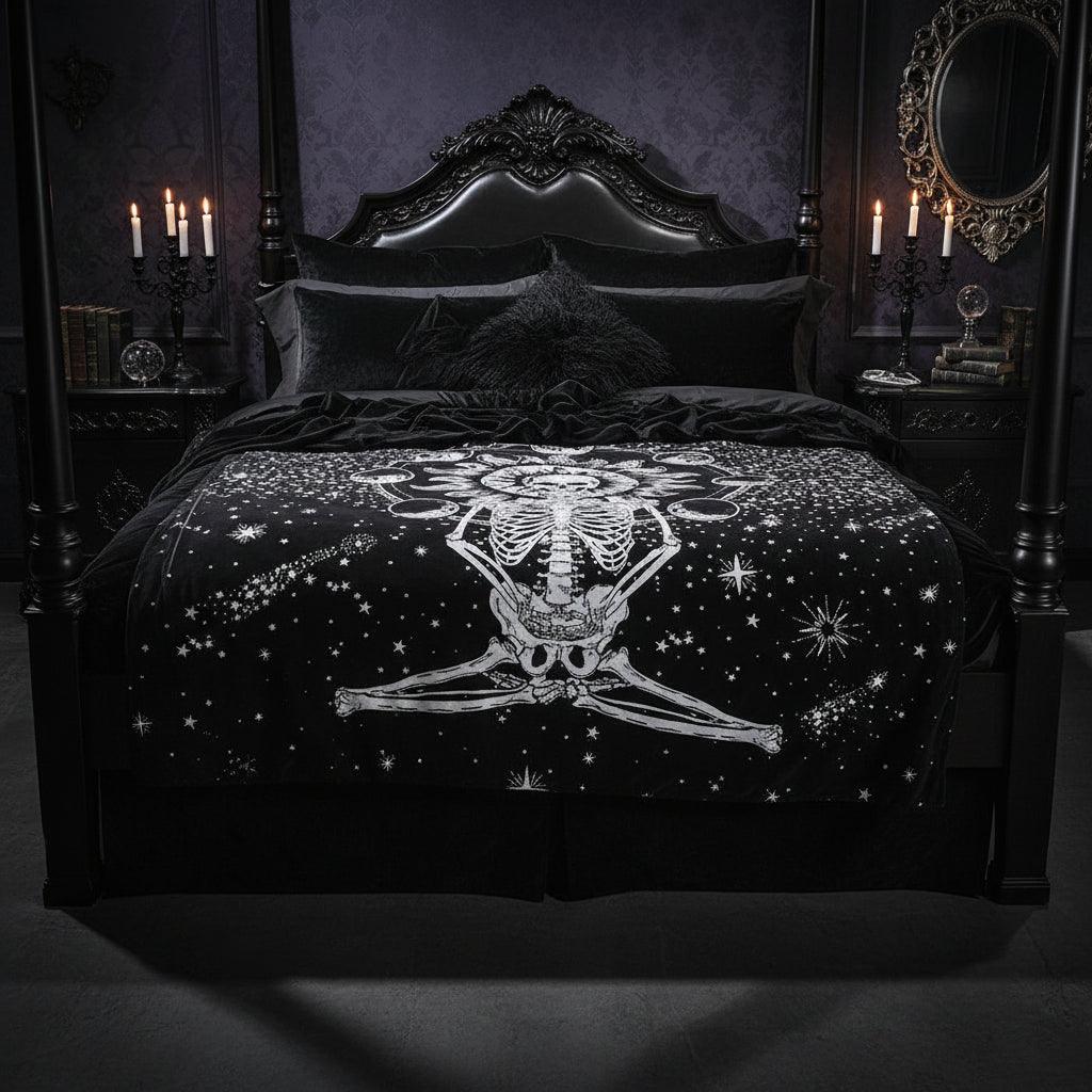 A black tapestry featuring a white celestial skeleton design with a sun, moon phases, and stars, hanging on a wall above a wooden floor with decorative vases and a picture frame.