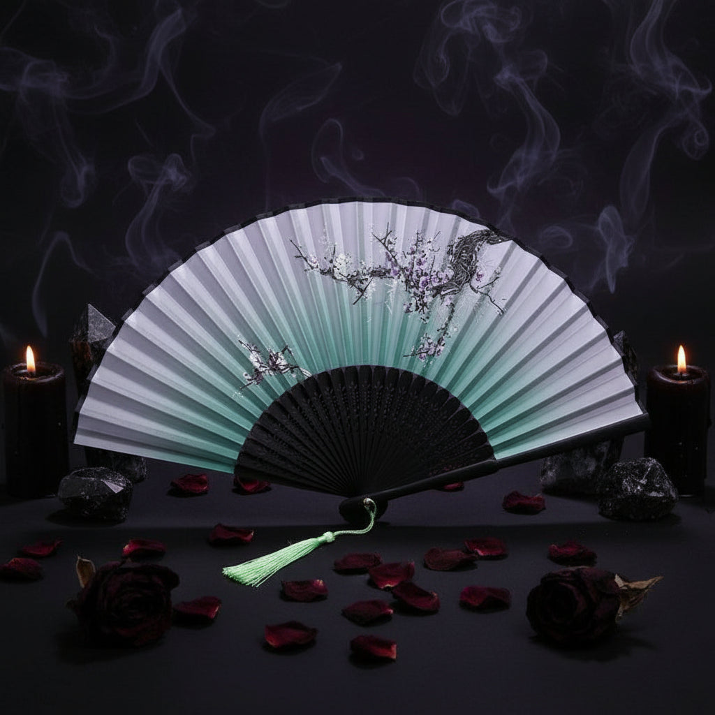 Traditional Chinese folding fan with black and green design on a white background with pink flowers.