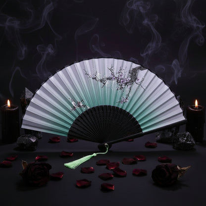 Traditional Chinese folding fan with black and green design on a white background with pink flowers.