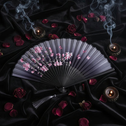 Black folding fan with floral design on a white background with pink flowers