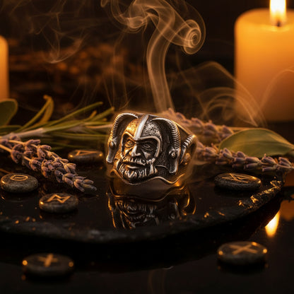A silver-toned Viking ring featuring a highly detailed horned helmet and face design, displayed on a reflective black surface.