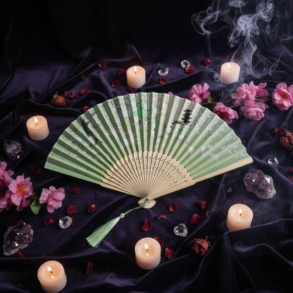 Traditional folding fan with green and white design on a light pink background with pink flowers.