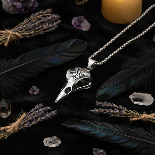 Silver bird skull pendant necklace held in a hand on a white background