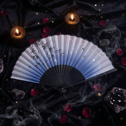 Traditional Chinese folding fan with black and white design on a light background with pink flowers.