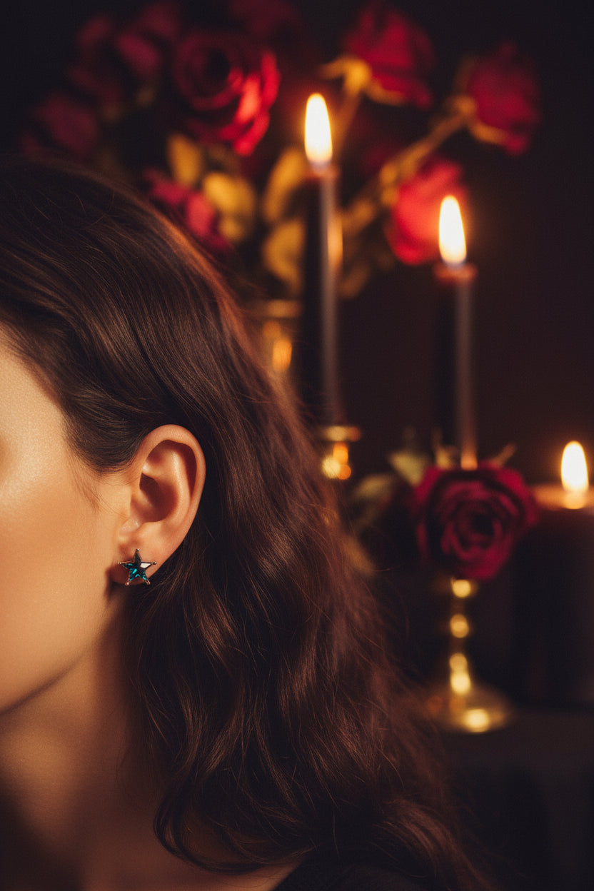 A pair of silver star-shaped stud earrings with iridescent blue-green gemstones, resting on a split beige and white background.