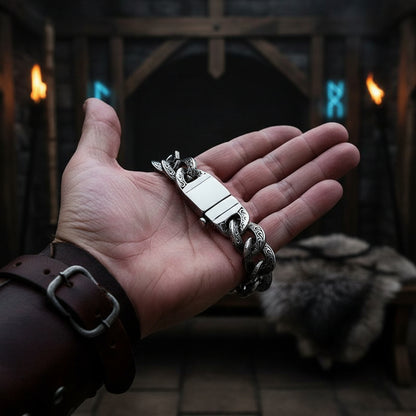 Silver chain bracelet held in a hand against a dark background