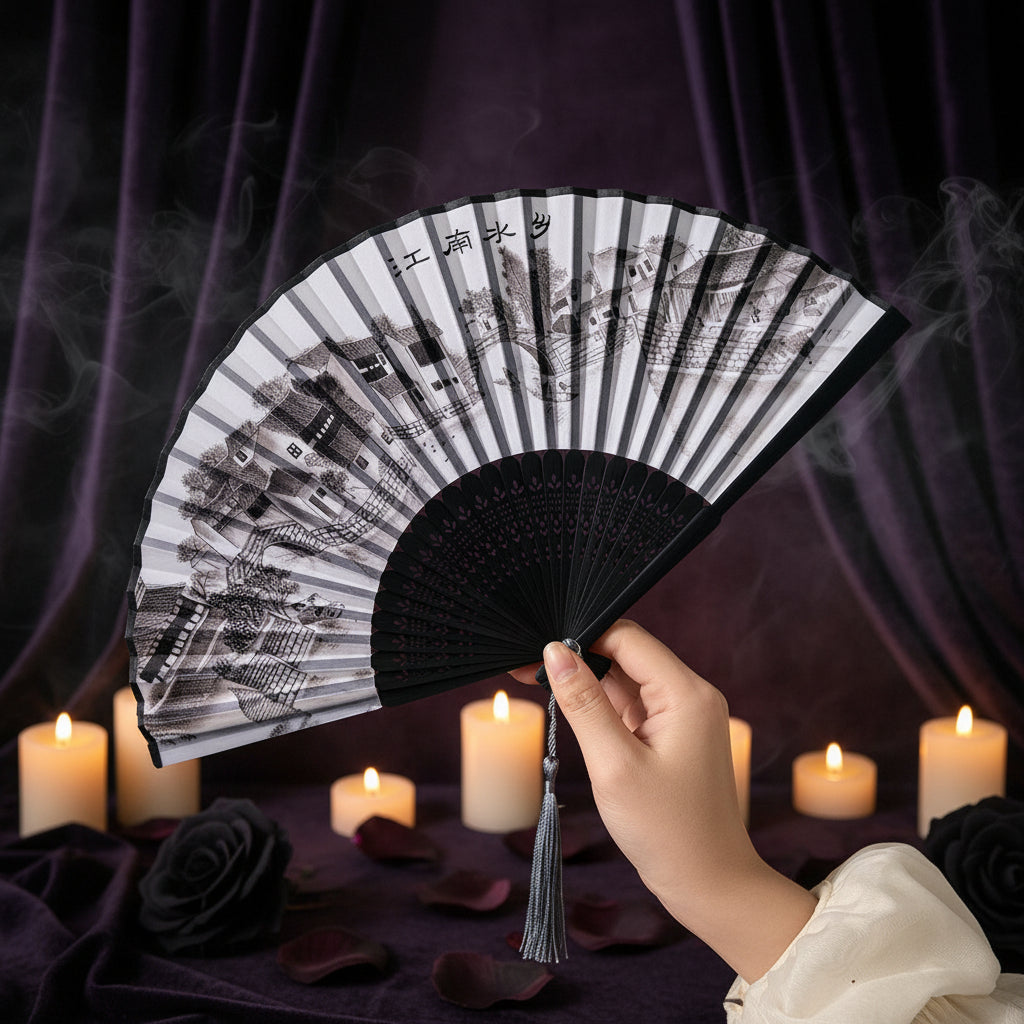 Hand holding a black and white patterned folding fan against a neutral background