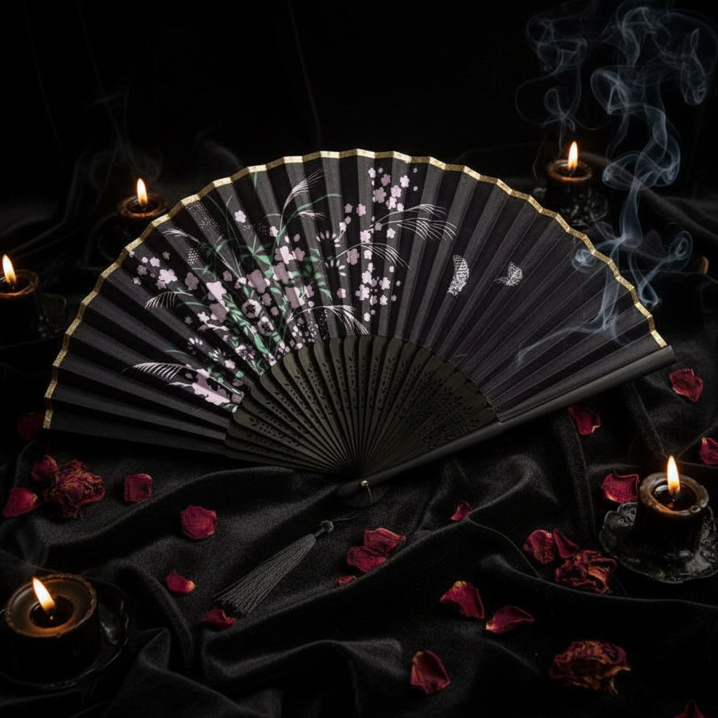 Black folding fan with floral design on a white background with pink flowers