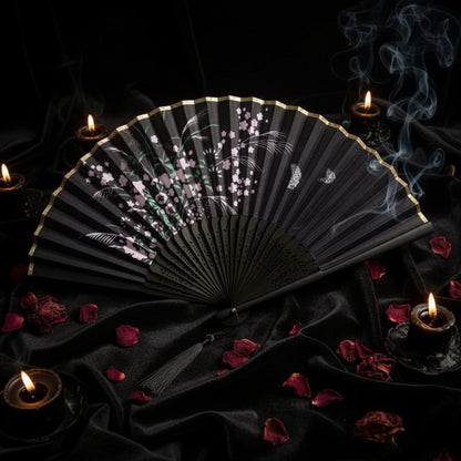 Black folding fan with floral design on a white background with pink flowers