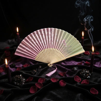 Colorful folding fan with pink tassel on a white background with cherry blossoms