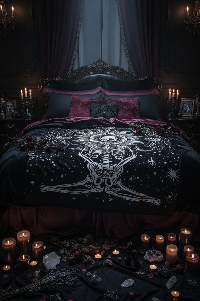 A black blanket featuring a white graphic print of a skeleton meditating in front of a sun and moon phases, shown flat against a white background.