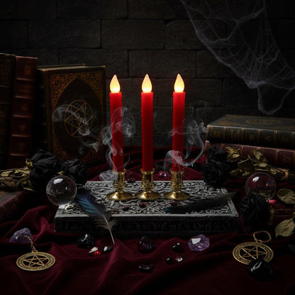 Three red taper candles with glowing flame tips in ornate gold holders, styled on a newspaper surface with books and flowers in a warm indoor setting.