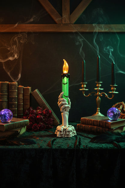 Halloween-themed candle with skeleton hand holder on a table with decorative items.