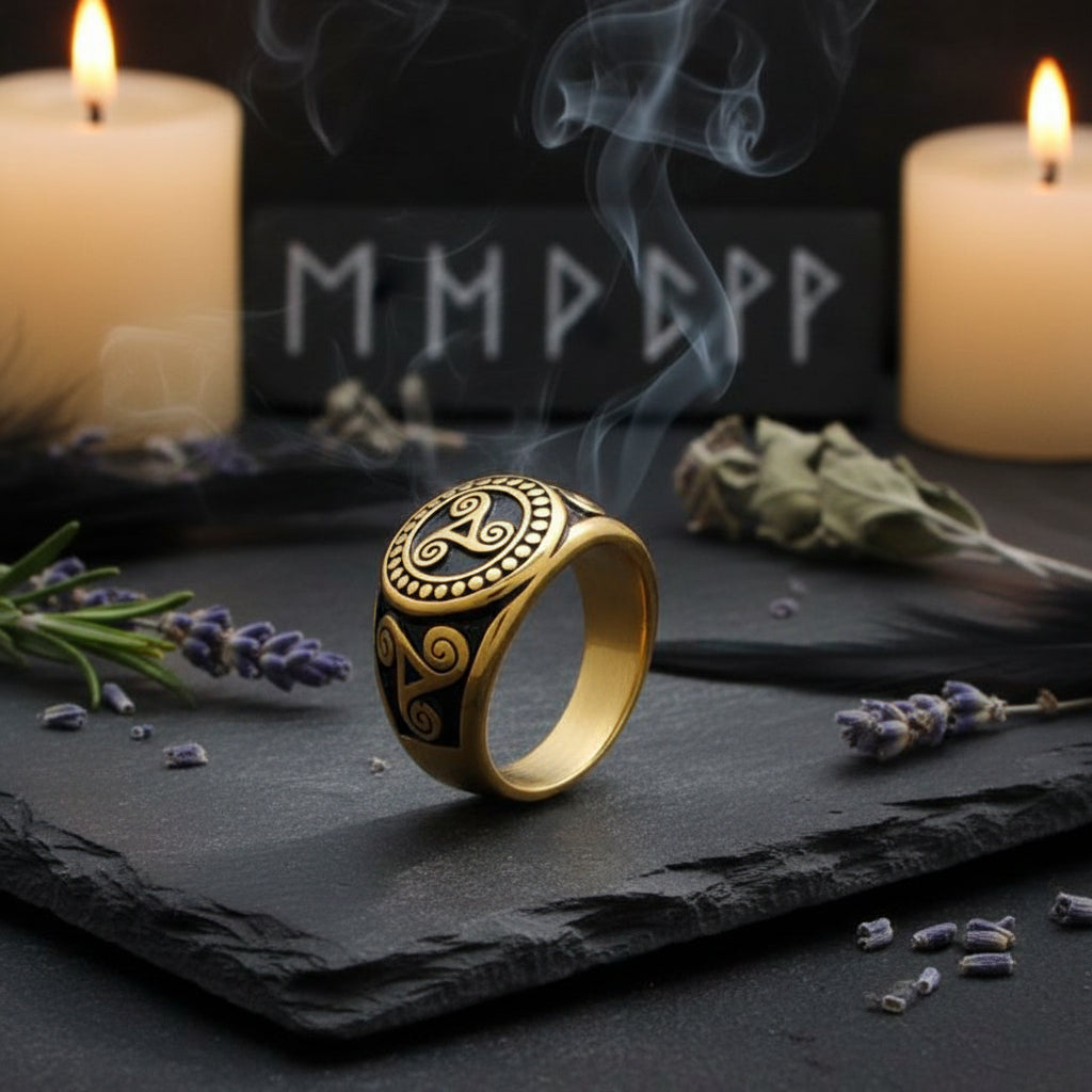 A gold and black Viking-style ring with a raised letter 'A' and ornate scrollwork, resting on a dark wood surface.