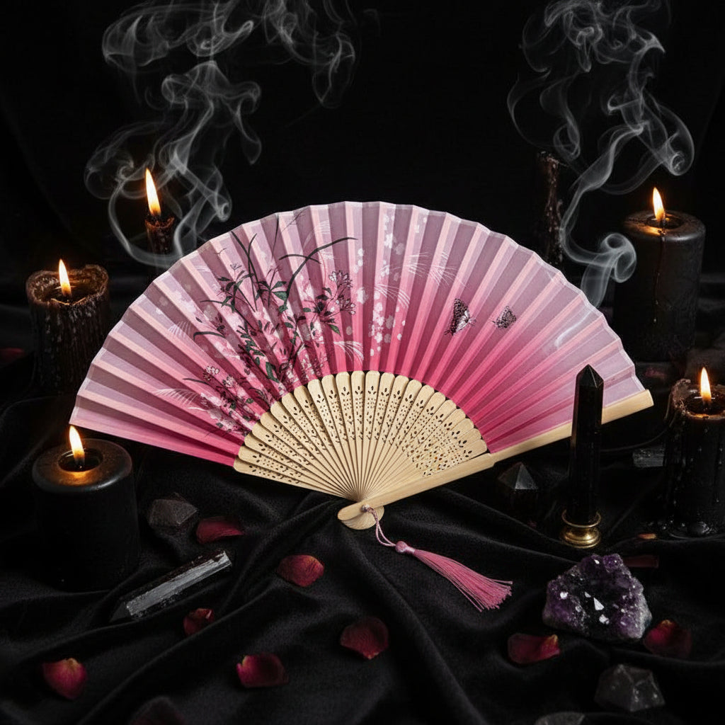 Pink and white folding fan with floral design on a light gray background with pink flowers.