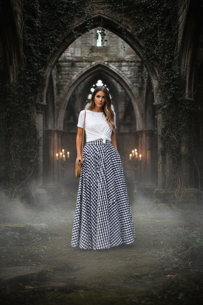 Person wearing a long black and white checkered skirt on a paved surface