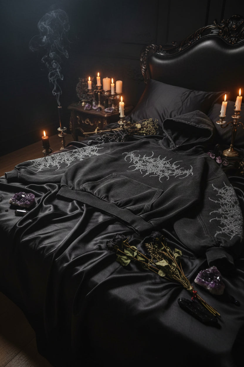 Black hoodie with intricate designs on sleeves and chest on a white background