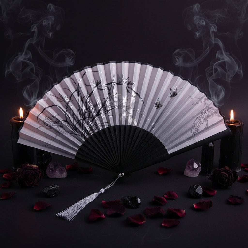 Black and white folding fan with floral design on a white background with pink flowers.