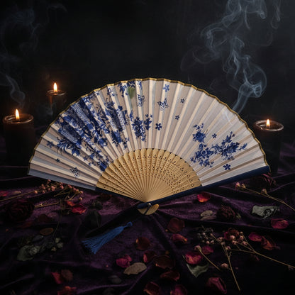Traditional folding fan with blue floral patterns on a white background with pink flowers.