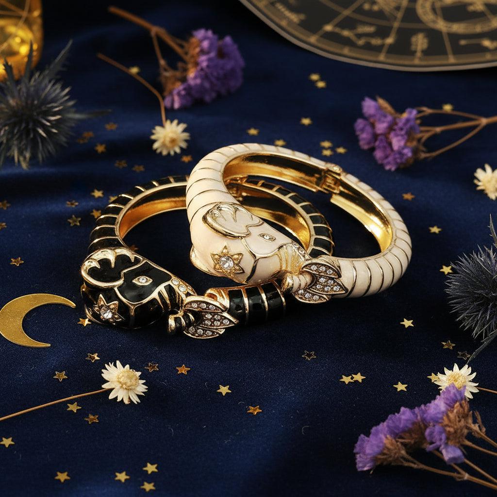 Pair of gold and black animal-themed earrings on a beige surface with a magazine in the background.