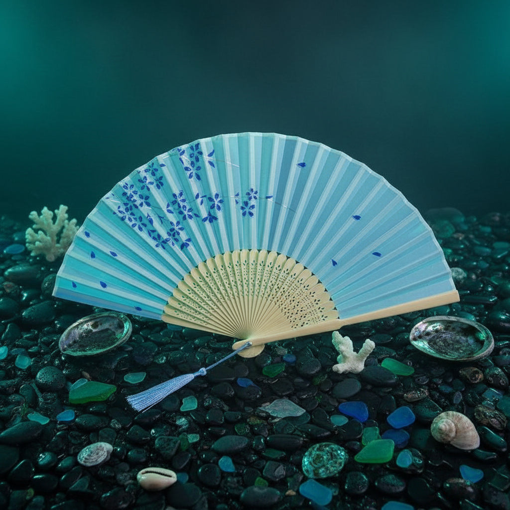 Light blue folding fan with floral design on a white background with pink flowers.