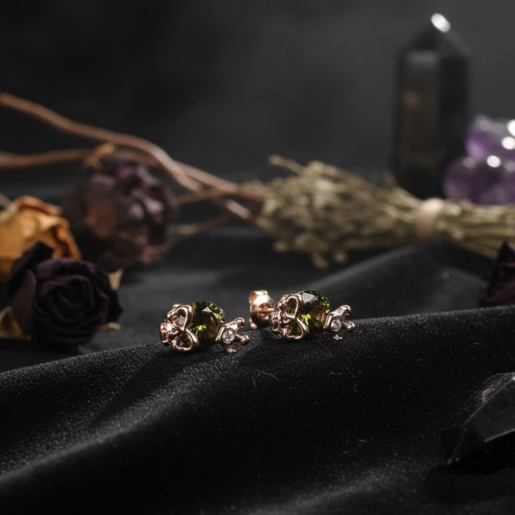 Rose gold earrings with green gemstones on a light gray background