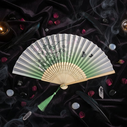 Traditional folding fan with floral design on a white background with pink flowers.