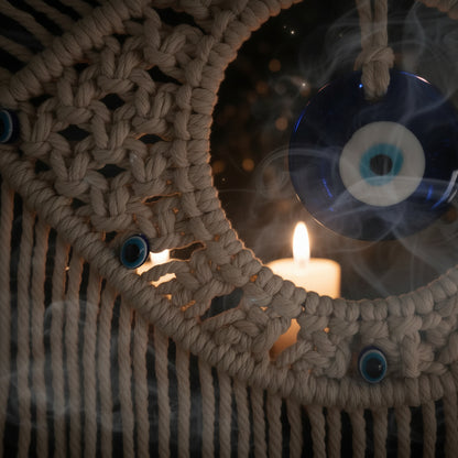 Close-up of a macrame wall hanging with blue evil eye charms.