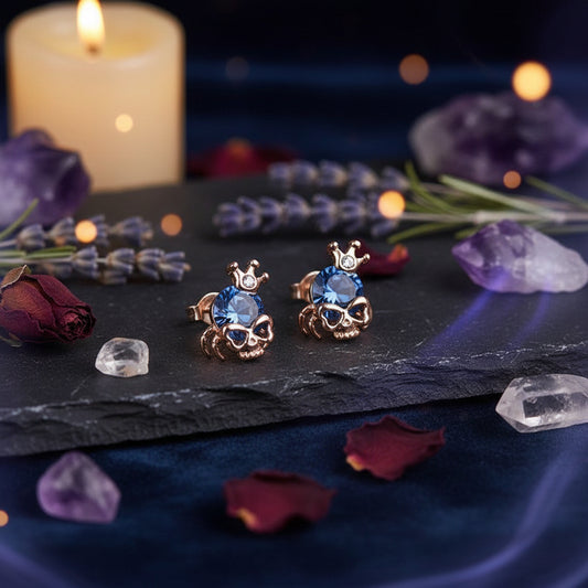 Pair of gold earrings with blue gemstones on a light gray background