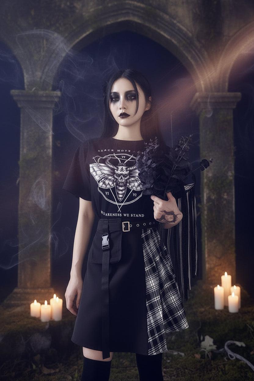 Person wearing a black t-shirt with a graphic design, holding dark flowers against a plain background
