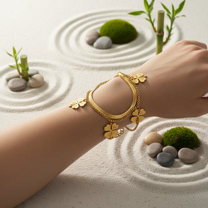 Gold bracelet with four-leaf clover charms on a beige box