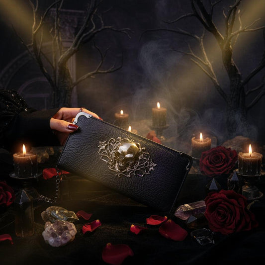 Black wallet with decorative clasp held by a person on a textured surface