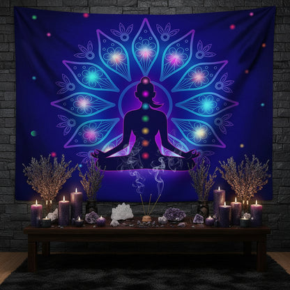A large wall tapestry featuring a meditating silhouette surrounded by a glowing mandala design in shades of purple, blue, and pink, displayed on a wall above a modern white sectional sofa in a living room setting.