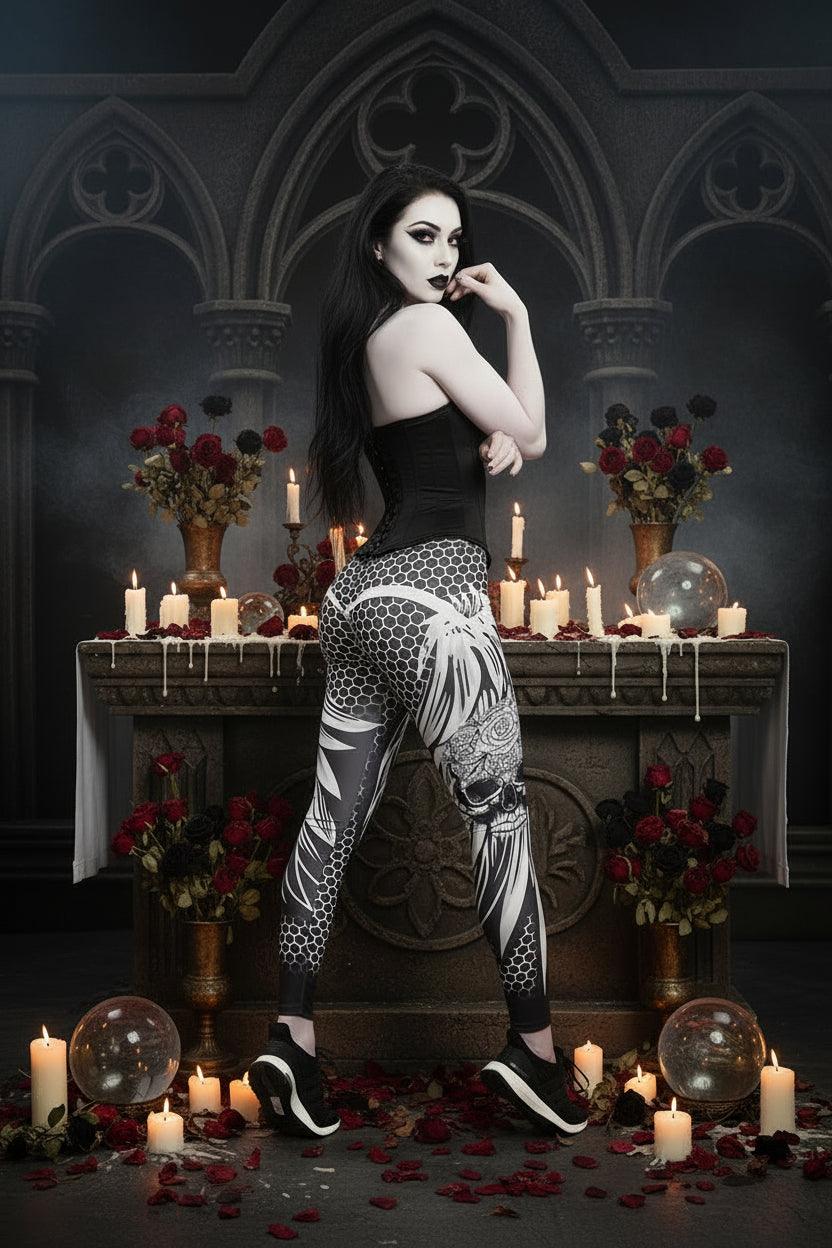 A woman modeling high-waisted athletic leggings with a black, white, and gray geometric and floral pattern, paired with a white sports bra and black sneakers, against a plain white studio background.