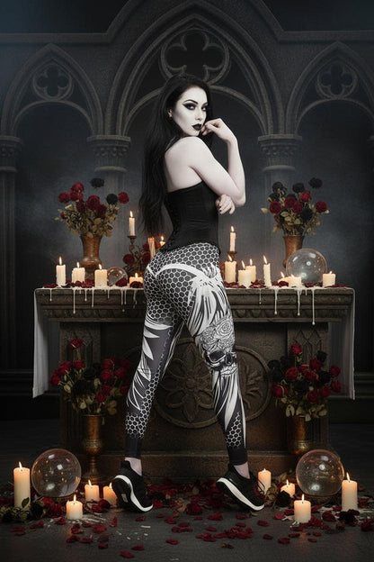 A woman modeling high-waisted athletic leggings with a black, white, and gray geometric and floral pattern, paired with a white sports bra and black sneakers, against a plain white studio background.