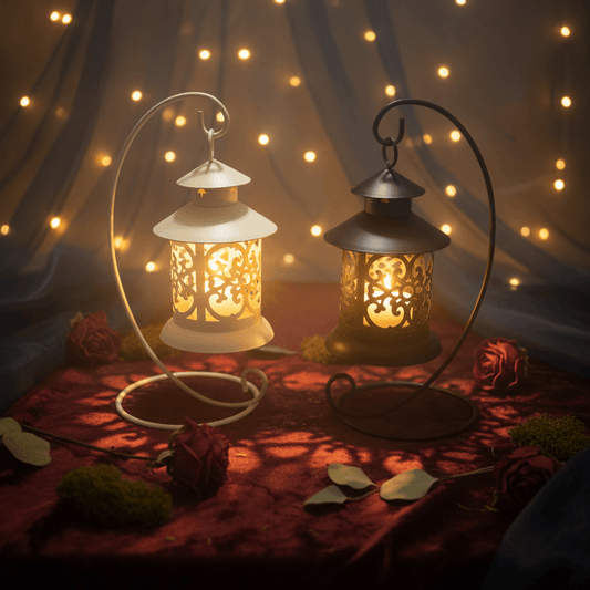Two decorative metal lanterns with hanging loops, one in cream and one in black, shown on a white background with a small green leaf prop.