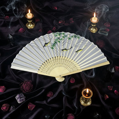 Handheld fan with floral design on a white tray with pink flowers