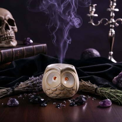 Ceramic owl-shaped oil burner on a wooden surface with a blurred background