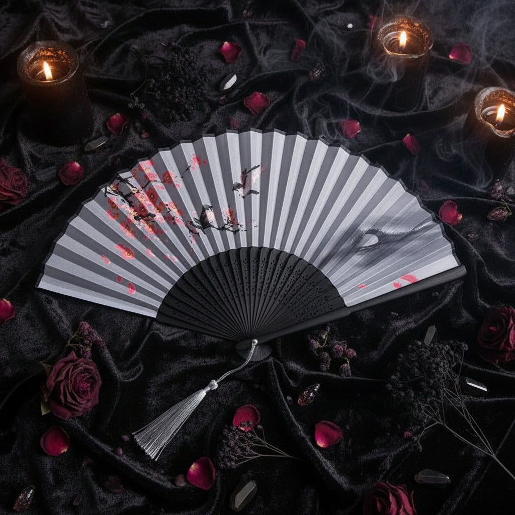 Black and white folding fan with floral design on a white background with pink flowers.