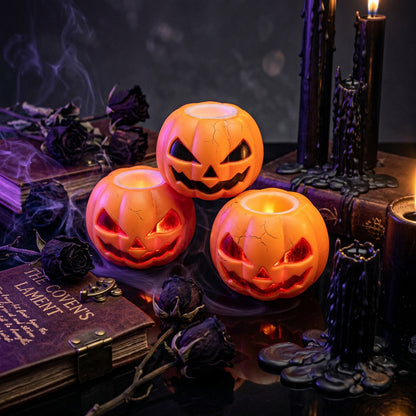 Three orange pumpkin-shaped candles with jack-o'-lantern faces on a white background