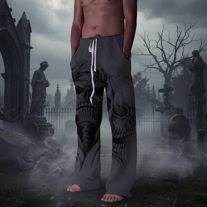 A person wearing loose gray drawstring pants with a large black skull graphic printed across the front, standing barefoot against a plain light gray wall.
