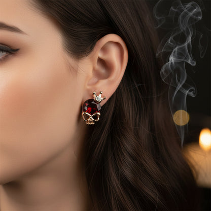 Pair of earrings with red gemstones and rose gold accents on a light gray background
