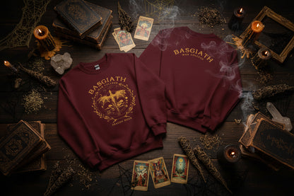 Two maroon sweatshirts with gold designs on hangers against a white background