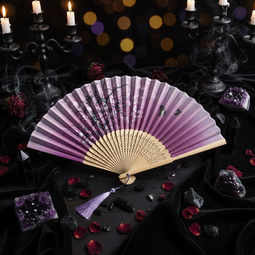 Pink folding fan with floral designs on a light gray background with pink flowers.